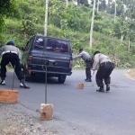 HEROIK: Memakai ganjal dari kayu, beberapa personel Polsek Senori membantu warga yang kesulitan naik di jalan tanjakan dan berkelok.