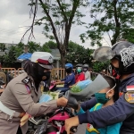 Salah satu Anggota Polwan Satlantas Polresta Sidoarjo saat membagikan buket masker kepada pengendara roda dua.