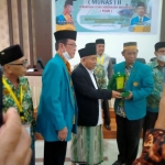 Prof Dr KH Asep Saifuddin Chalim, MA, mendapat cindramata dari Ketua Panitia Munas II PGMI, Dr Kaswad Sartono, disaksikan Ketua Umum PGMI Syamsudin di Ruang Bir Ali Asrama Haji Makassar, Sabtu (4/12/2021). Foto: M Mas