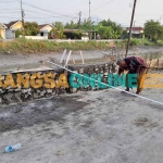 Warga mengukur jalan di samping proyek plengsengan di Desa Kemantren, Kecamatan Tulangan, Sidoarjo. Foto: MUSTAIN/BANGSAONLINE