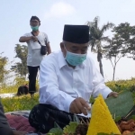 Kiai Asep memotong tumpeng tanda diresmikannya lahan yang disiapkan untuk percontohan pertanian, peternakan, dan perikanan.