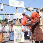 Ning Ita Bersama emak-emak Kota Mojokerto saat menggantungkan bahan makanan yang bisa diambil secara gratis oleh warga yang membutuhkan.