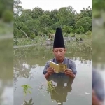 Hartono, warga Gading Watu, Kecamatan Menganti, Gresik, saat berdoa di makam yang terendam banjir. Foto: Ist
