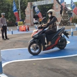 Seorang polisi penguji tengah mengamati pemohon SIM yang mencoba lintasan baru di Polres Mojokerto.