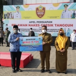 Kepala Dispol PP Gresik Abu Hasan menyerahkan bantuan beras secara simbolis kepada Bupati Gus Yani didampingi Bu Min. (foto: SYUHUD/ BANGSAONLINE)