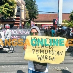 Binti, orang tua salah satu korban dugaan penganiayaan (pemukulan) oleh oknum, saat membentangkan poster di depan Mapolres Kediri Kota. Foto: MUJI HARJITA/BANGSAONLINE