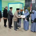 Ketua Baznas Jatim, KH Muhammad Roziqi bersama Kepala Kanwil Kemenag Jatim H Husnul Maram saat memberikan santunan beasiswa secara simbolis. Foto: Yudi Arianto/BANGSAONLINE.com