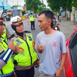 Polisi memberikan penjelasan kepada pengendara yang kedapatan merokok di dalam mobil.