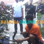 Tersangka saat menunjukkan besi hasil pencurian ke polisi. Foto: RUSMIYANTO/BANGSAONLINE