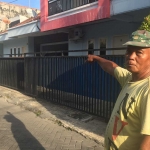 Salah satu warga yang menunjukkan lokasi penggerebekan rumah kos yang diduga sebagai penimbun rokok ilegal di Jalan Leo, Karang Empat Surabaya, Kamis (27/6/2024). Foto: Rusmiyanto/BANGSAONLINE.com