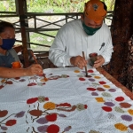 MENCOBA: Cabup BHS mewarnai motif batik tulis saat mengunjungi Rumah Batik Al Huda di Sepande, Candi, Senin (5/10/2020). (foto: MUSTAIN/ BANGSAONLINE)