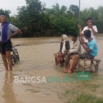 Sejumlah warga Desa Lebaksari sedang menunggu jemputan perahu untuk bisa sampai ke TPS. foto: EKY NURHADI/ BANGSAONLINE