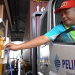 Seorang pengemudi truk sedang membuka gate secara mandiri.