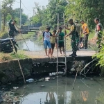 Satgas TMMD ke-120 bersama anak-anak ketika membersihkan irigasi Desa Penambangan. Foto: Ist