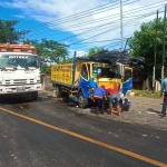 Petugas dibantu warga berupaya mengevakuasi salah satu truk yang terlibat laka. 