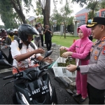 Kapolres Gresik, AKBP Adhitya Panji Anom bersama istri saat bagi-bagi takjil kepada pengguna jalan. Foto: SYUHUD/ BANGSAONLINE.com
