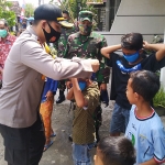 Kapolres Lamongan, AKBP Harun saat membagikan masker secara door to door. (foto: TRIWIYOGA/BANGSAONLINE).