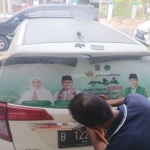 Kader Gerakan Pemuda Ansor Pamekasan saat membranding MTQ XXIX Jatim di kaca belakang mobilnya.