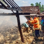 Petugas Damkar Tuban saat melakukan pembasahan terhadap tumpukan jerami yang terbakar.