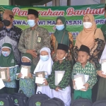 Ketua UPZ Kemenag Lamongan, Imam Hambali, saat menyerahkan bantuan berupa peralatan sekolah kepada siswa