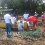 Sejumlah warga Dusun Kalangan, Desa Kalangsemanding, Kecamatan Perak menempel tulisan ke alat berat proyek berisi penolakan pembangunan perumahan daerahnya, Senin (2/1). foto: ROMZA/ BANGSAONLINE 