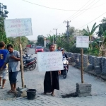 Warga Desa Gluranploso Kecamatan Benjeng saat menggelar aksi di lokasi perbaikan jalan poros desa (JPD).