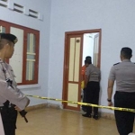 Petugas memasang police line di kamar tempat ditemukannya dua jenazah.