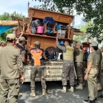 Petugas Satpol PP Kabupaten Kediri saat menaikkan gerobak/rombong milik PKL yang terkena penertiban.