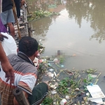 Warga menunjukkan mayat bayi yang ditemukan di Sungai Sukodono, Sidoarjo.