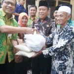 Bupati Fadeli (tengah) saat menyerahkan paket sembako murah kepada salah satu warga.