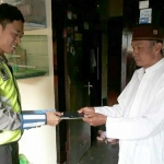 Dua anggota Satlantas Polres Pasuruan Kota saat menyerahkan BPKB kepada pemiliknya, Senin (04/01/2019). foto: ANDY F/ BANGSAONLINE 