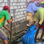 Petugas saat membersihkan selokan di Pasar Ikan Lamongan.