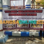 Pemuda di Desa Daleman saat memasang banner di pintu utama gedung DPRD Sampang. Foto: MUTAMMIM/BANGSAONLINE