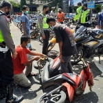 Petugas kepolisian saat menyaksikan pemuda yang mengganti suku cadang sesuai standar di hadapan orang tuanya.