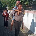 Bripka Purnomo saat menggendong nenek Sri Sutini menuju TPS.