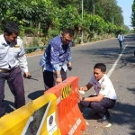 Bagus AJ dan Hery Wahyu Rianto saat memasang mata kucing di separator perempatan Jalan Tri Dharma. foto: Syuhud/bangsaonline.com