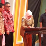 Gubernur Jwa Timur Khofifah menandatangani komitmen bersama antara Gubernur Jatim, Kepala OJK Regional IV Jatim dan Plt. Pgs. Direktur Utama Bank Jatim saat Rakor Provinsi Jatim Tahun 2019 di Grand City Surabaya, Jumat lalu (22/11/2019). foto: istimewa/ bangsaonline.com