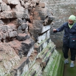 Salah seorang pengunjung saat mengamati kaki Candi Dorok yang tampak berlumut. (foto: MUJI HARJITA/ BANGSAONLINE)