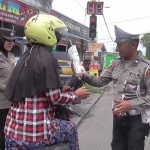 Anggota Polsek Wonoayu saat memberikan buket bunga berisi coklat kepada para pengguna jalan di Simpang 4 TL Wonoayu, Sidoarjo, Rabu (15/2/2023)