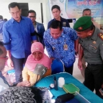 PEDULI: Camat Sedati Ridho Prasetya (tengah) didampingi Kades Banjarkemuning Zainul Abidin (kiri), saat baksos di Desa Banjarkemuning Sedati, Senin (17/4). foto: mustain/ BANGSAONLINE