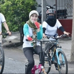 Novita Hardiny (tengah) naik ontel sambil bagi-bagi masker. foto: HERMAN/ BANGSAONLINE