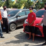 Tersangka Ishak Maulana beserta barang bukti mobil yang digadaikan saat dipamerkan ke awak media. 