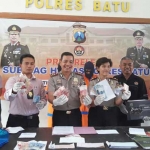 Kapolres Batu AKBP Leonardus Simarmata saat menunjukkan tersangka pungli dan barang bukti.