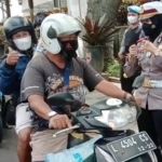 Kasatlantas AKP Indah Citra Fitriani saat memberikan hadiah kepada pengendara yang melintas di Jalan Diponegoro, Kota Batu.