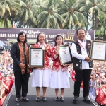 Bupati Jember Hendy Siswanto (kanan) menunjukkan piagam Muri atas permainan alat musik angklung dengan jumlah pasangan terbanyak.