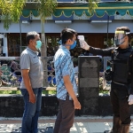 Para jemaah Masjid Al Muhajirin sedang diukur suhu tubuh oleh petugas Linmas.