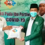 Anggota Komisi V DPR RI H. Syafiuddin Asmoro saat menyerahkan paket sembako secara simbolis kepada KH. Makki Nasir, Ketua PCNU Bangkalan.