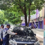 Petugas Dishub Tuban sedang menempelkan stiker peringatan terakhir bagi pemilik mobil.