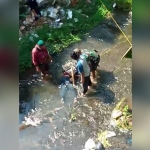 Warga mengevakuasi korban dari Sungai Brantas untuk diserahkan pada keluarganya.