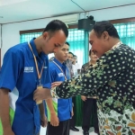 Asisten II Bidang Perekonomian dan Pembangunan Pemkab Bojonegoro, Setyo Yuliono (baju batik) sedang memberikan id card kepada perwakilan peserta.